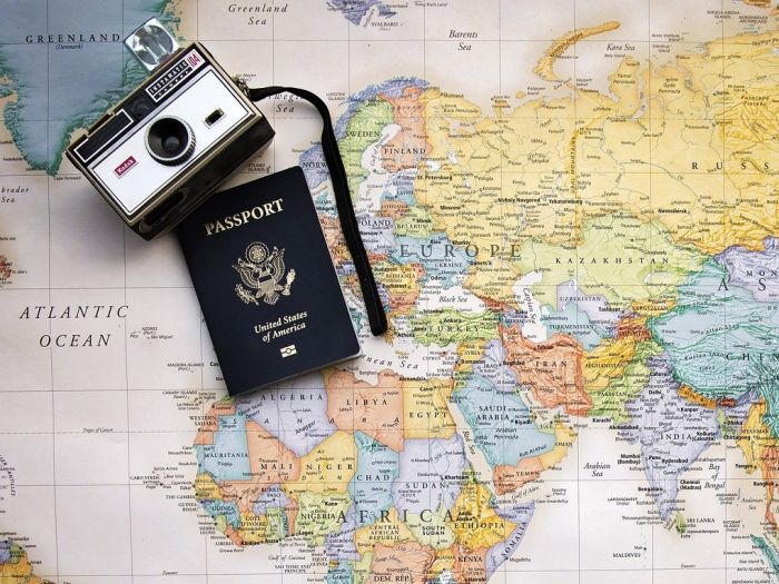 世界地図の上に置いたパスポートとカメラ